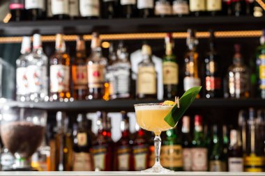 Sarı limon kokteyli ile süslenmiş cam ananas ve nane ile bulanık tezgah arka planında.