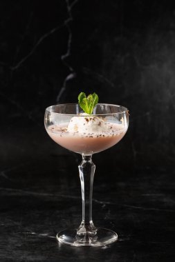 Bir bardak buzlu Baileys kokteyli. Siyah bir arka fona yerleştirilmiş nane yaprağı ile süslenmiş.