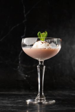 Bir bardak buzlu Baileys kokteyli. Siyah bir arka fona yerleştirilmiş nane yaprağı ile süslenmiş.