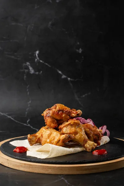 Kurutulmuş bufalo tavuk kanatları susam tohumları, soğan ve kırmızı biber dilimleri siyah ahşap tahtada..