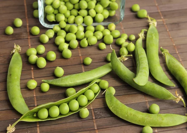 Grüne Erbsenschoten auf Holztisch — Stockfoto