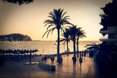 Mallorca Santa Ponsa sahilde günbatımı sırasında yürüyen turist