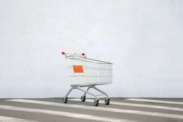 Un carrello vuoto al supermercato. Carrello della spesa sul White Wall Store. Carrello Carrello Carrello Si trova vicino al centro commerciale con spazio copia. Venerdì nero. Vista laterale. Shopping online. Concetto di shopping. Commercio elettronico — Foto Stock