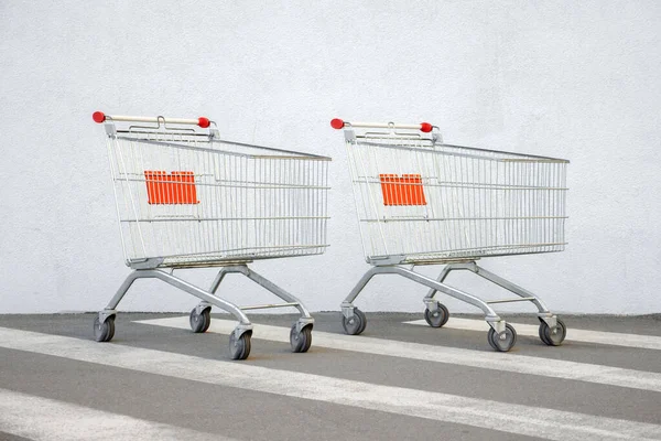 Дві порожні картки Grocery Cart на Білій стіні. Троллі на фоні Супермаркету. Електронна комерція. Shopping Online (англійською). Сторона зору. Машинний магазин Cart Trolley Stands at Mall with Copy Space. Продаж чорної п "ятниці — стокове фото