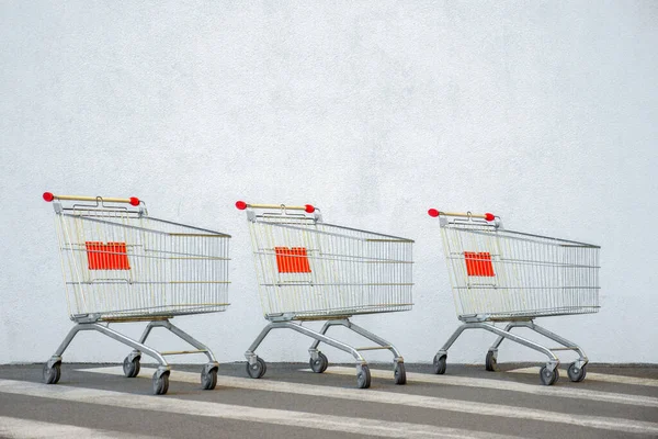 Tre sportelli vuoti del carrello del carrello vicino al centro commerciale con spazio copia. Carrello della spesa sul White Wall Store. Carrello al supermercato. E-commerce. Concetto di shopping. Vista laterale. Venerdì nero Vendita. Online — Foto Stock