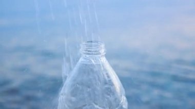 Doğal İçme Saf Suyu. PET şişesinin üzerine düşen damlalar. Güzel Su Damlaları Mavi Su Arkaplanındaki Temiz Su ile Doldurulmuş Boş Şeffaf Plastik Şişeye Döküldü. Deniz