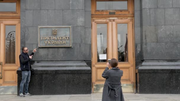 Touristen werden vor der Hintergrundtafel mit der Aufschrift - Präsident der Ukraine an der Tür des Haupteingangs zur Verwaltung des Präsidenten der Ukraine in Kiew fotografiert. Politik