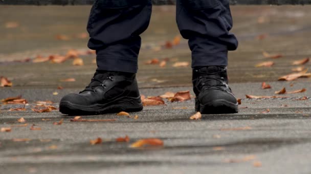 Herfst. Details. Militaire laarzen aan de mannenvoeten. Policemans voeten. Laarzen van politieagent in uniform. De benen van een politieagent sluiten de wacht. Voeten van bewaker in zwarte laarzen. Gevallen bladeren — Stockvideo