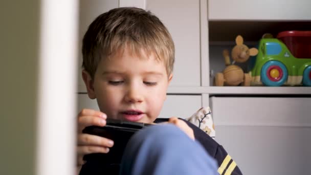 Crianças problemas com gadget. joguinho no smartphone. Rapaz usa smartphone. Criança jogando videogame no telefone. As crianças usavam gadget. Geração alfa. Um miúdo a jogar telemóvel. Nova geração — Vídeo de Stock