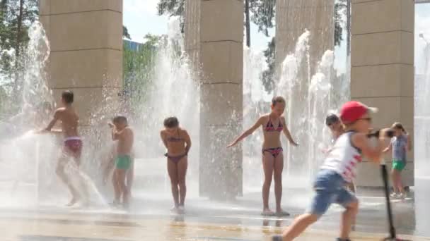 Silhouettes children have fun between in fountain on Street. Kids play water in fountain. Child play fountain jets. Happy children in summer heat in park fountain. Landscaping city. City park summer — Stock Video