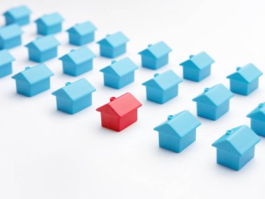Home choice or selection property and real estate. Red house model among blue toy houses on white color background. Unique house different from group of same type miniature houses. Property marketing clipart