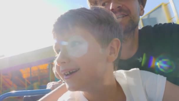 Selfie di padre e figlio godendo di equitazione estrema attrazione montagne russe in giostre parco a tema o luna park. Close up bambino sorridente con papà felice nel parco divertimenti divertirsi sul giro sulle montagne russe — Video Stock