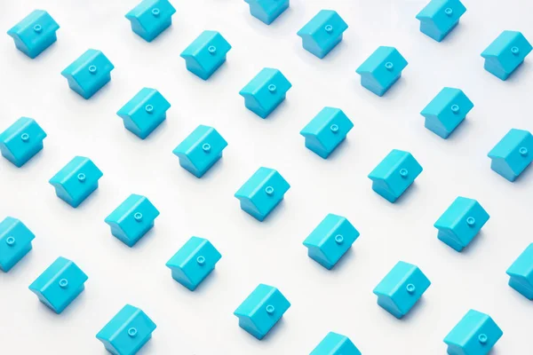 Real estate or property market cottage home. Abstract model village or city district construction new neighborhood pattern of many blue miniature small toy houses stand a rows on white minimal design