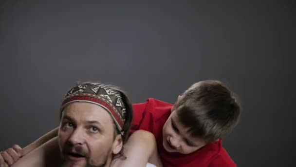Piggyback father and son falling down. Having fun with dad spinning kid fool around with father smile boy. Family fun boy and father holding his son on shoulders dad whirling child enjoy time together — Stock Video