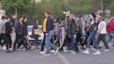 Yaya geçidi. Trafik sıkışıklığı. Kalabalık ağır çekimde yürüyor. Yoldan karşıya geçen kalabalık bir şehir. Kalabalık insanlar büyük şehirde sokak trafiğini geçiyor. Birçok araba sokağı