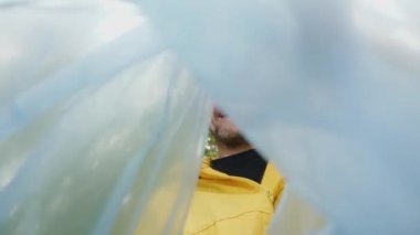 Çevre koruma gönüllüsü bir ormanı temizliyor. Ekoloji kirliliği doğadaki plastik atıkları temizliyor. Doğayı kurtar. Çöp torbasının içinden gönüllü yüz temizleme parkı görüntüsü. Fedakarlık