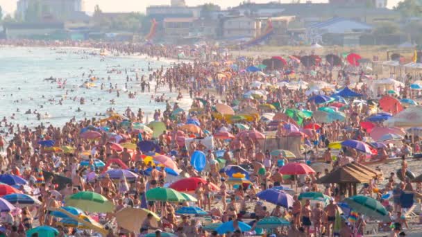 海滨度假期间休息的人.海洋,太阳,海滩,休息,度假,旅行的概念.海滩上挤满了人，还有太阳伞。海滨有很多游客。缓慢运动的海滩拥挤的场景海 — 图库视频影像