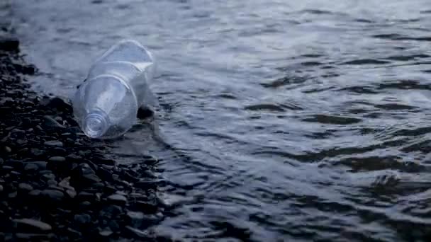 Sticlă goală de gunoi din plastic care se află pe malul râului. Aruncat deșeuri de plastic de gunoi de apă râu. Poluarea ecologică. Probleme de mediu poluarea râurilor gunoi apă gunoi plastic ocean gunoi — Videoclip de stoc