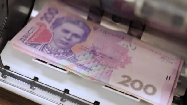 Ukrajinské bankovky ve stroji na počítání měn přepočítávají peněžní hřivnu na bankovky UA. Počítám hryzniovy bankovky. Closeup cash Ukrainian money counting machine counting 200 hryvnias bills UA — Stock video