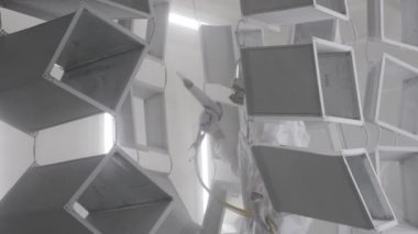 Endüstriyel boya, metal tozu kaplama boya üretim süreci. Metal ürünlerin toz tabakası. Parça parça metal atölyesini sprey tabancayla boyayan kapak çalışanı. Metal işçiliği fabrika boyası