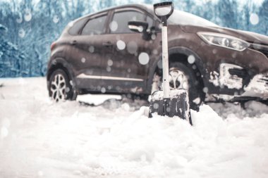 Arabanın yanındaki küreği kapat. Otomatik arka planda bulanıklık. Ulaşım, kış, karda sıkışmış bir araç. konsept. 