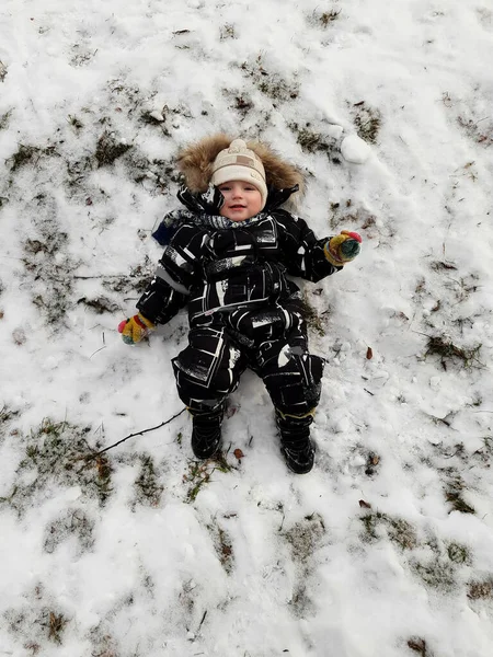 A European boy lies in the snow in winter. A happy and joyful boy is resting. — Stock Photo, Image