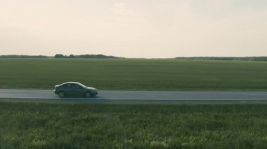 Bir tarlada yolda giden bir arabanın hava görüntüsü.