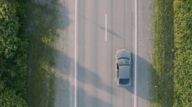 Bir tarlada yolda giden bir arabanın hava görüntüsü.