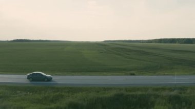 Bir tarlada yolda giden bir arabanın hava görüntüsü.