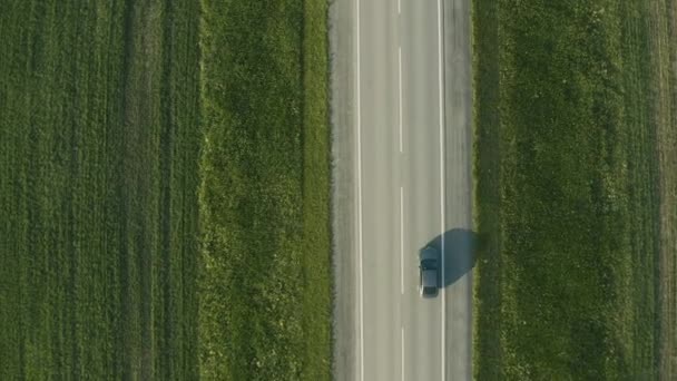 Vista aérea de un coche conduciendo en la carretera en un campo — Vídeo de stock