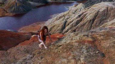 Kızıl dağlara elbisesiyle tırmanan bir kızın hava manzarası.