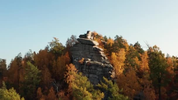Vista aérea de un acantilado rodeado por un colorido bosque otoñal al atardecer — Vídeos de Stock