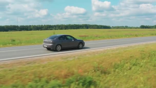 Luchtfoto van een rijdende auto op de weg in een veld bij zonnig weer — Stockvideo