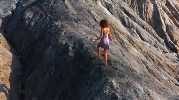 Luchtfoto van een meisje dat de rode bergen beklimt in een jurk — Stockvideo