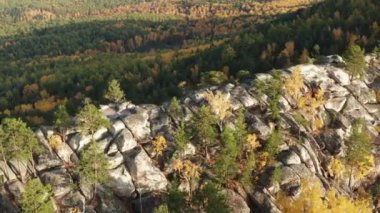 Gün batımında renkli bir sonbahar ormanıyla çevrili bir uçurumun havadan görünüşü.