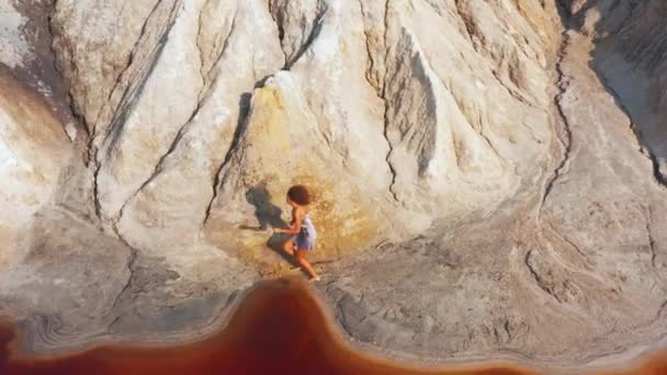 Luchtfoto van een meisje dat de rode bergen beklimt in een jurk — Stockvideo