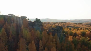 Gün batımında renkli bir sonbahar ormanıyla çevrili bir uçurumun havadan görünüşü.