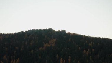 Gün batımında renkli bir sonbahar ormanıyla çevrili bir uçurumun havadan görünüşü.