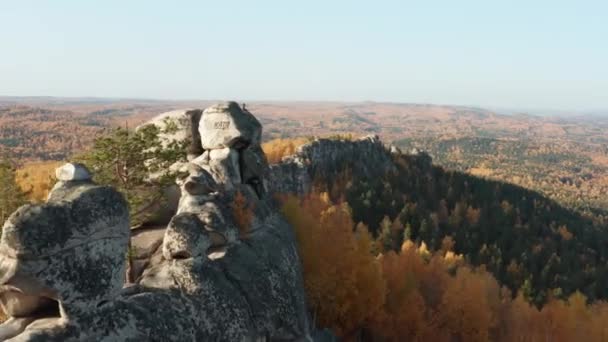 Vista aérea de un acantilado rodeado por un colorido bosque otoñal al atardecer — Vídeos de Stock
