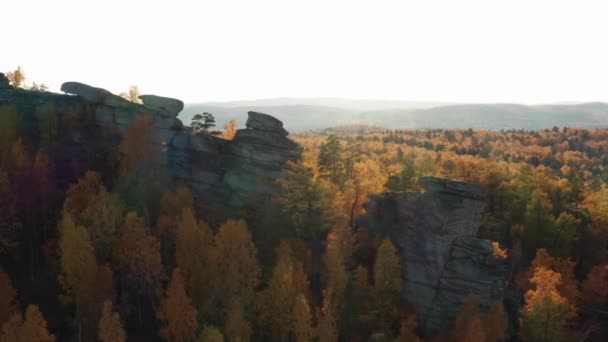 Vista aérea de un acantilado rodeado por un colorido bosque otoñal al atardecer — Vídeos de Stock