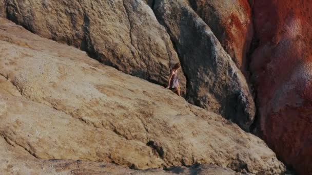 Vista aérea de una chica que sube las montañas rojas en un vestido — Vídeos de Stock