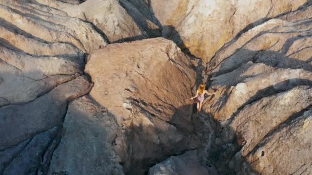 Vista aérea de una chica que sube las montañas rojas en un vestido — Vídeos de Stock