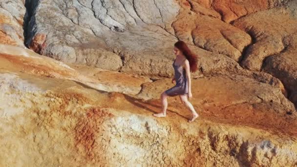 Vista aérea de una chica que sube las montañas rojas en un vestido — Vídeos de Stock