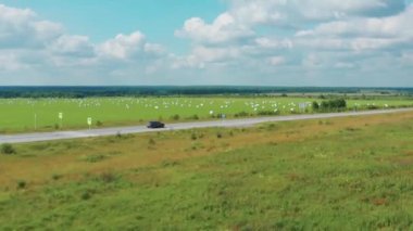 Güneşli bir havada, yolda giden bir arabanın hava görüntüsü.