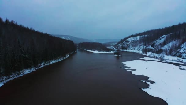 Uitzicht vanuit de lucht op de rivier met heuvels en sneeuwwoud aan de oevers — Stockvideo