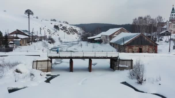 Вид с воздуха на сноуборд, пересекающий мост зимой — стоковое видео