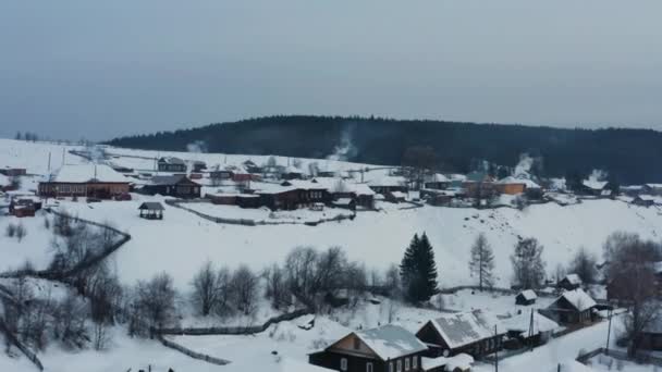 Aerial view of smoke coming from stoves in wooden houses in the village in winter — Stock Video