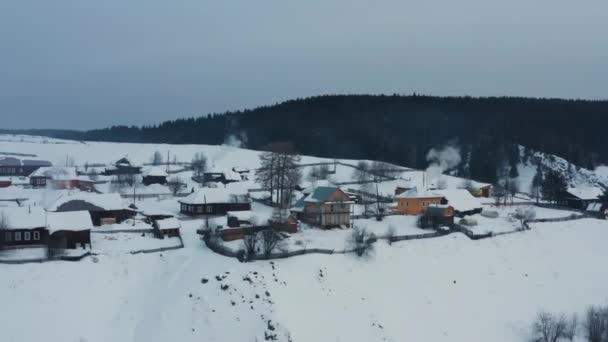 Vista aérea del humo procedente de estufas en casas de madera en el pueblo en invierno — Vídeo de stock