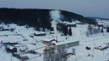 Kışın köydeki ahşap evlerdeki ocaklardan çıkan dumanların hava manzarası.
