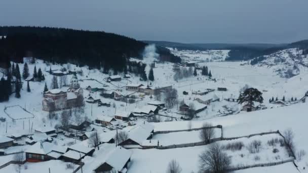 Kışın köydeki ahşap evlerdeki ocaklardan çıkan dumanların hava manzarası. — Stok video